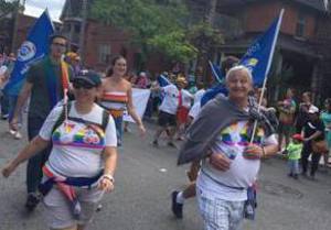 Four people walking in the Ottawa Pride parade, carrying blue PIPSC flags