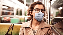 Une femme assise sur un autobus portant un masque bleu non médical.